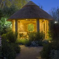 Wooden chair in thatched summerhouse lit at night